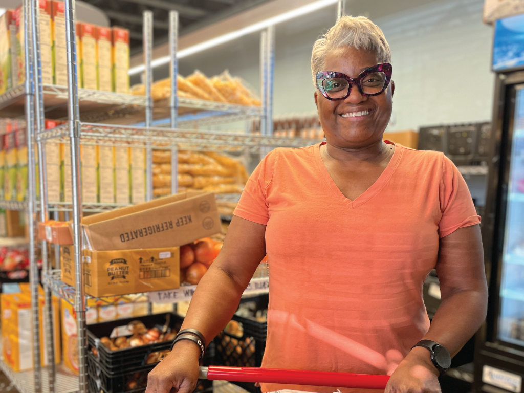 Woman leaning on shopping cart in pantry aisle. 